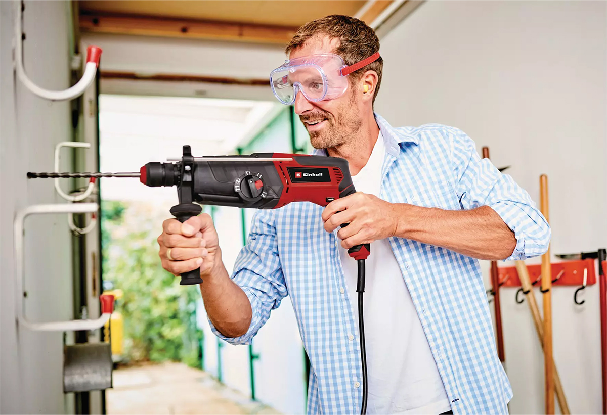 Απεικονίζεται άνδρας με προστατευτικά γυαλιά να χρησιμοποιεί το πιστολέτο στον τοίχο.